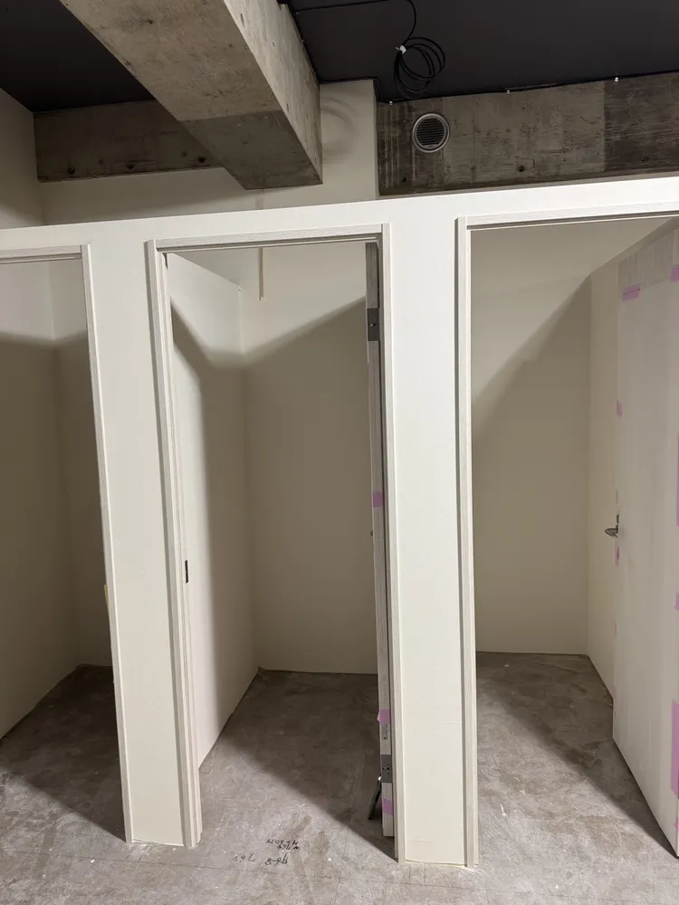クロスを貼り終えた店舗の試着室ブース。建具の養生テープが残っている