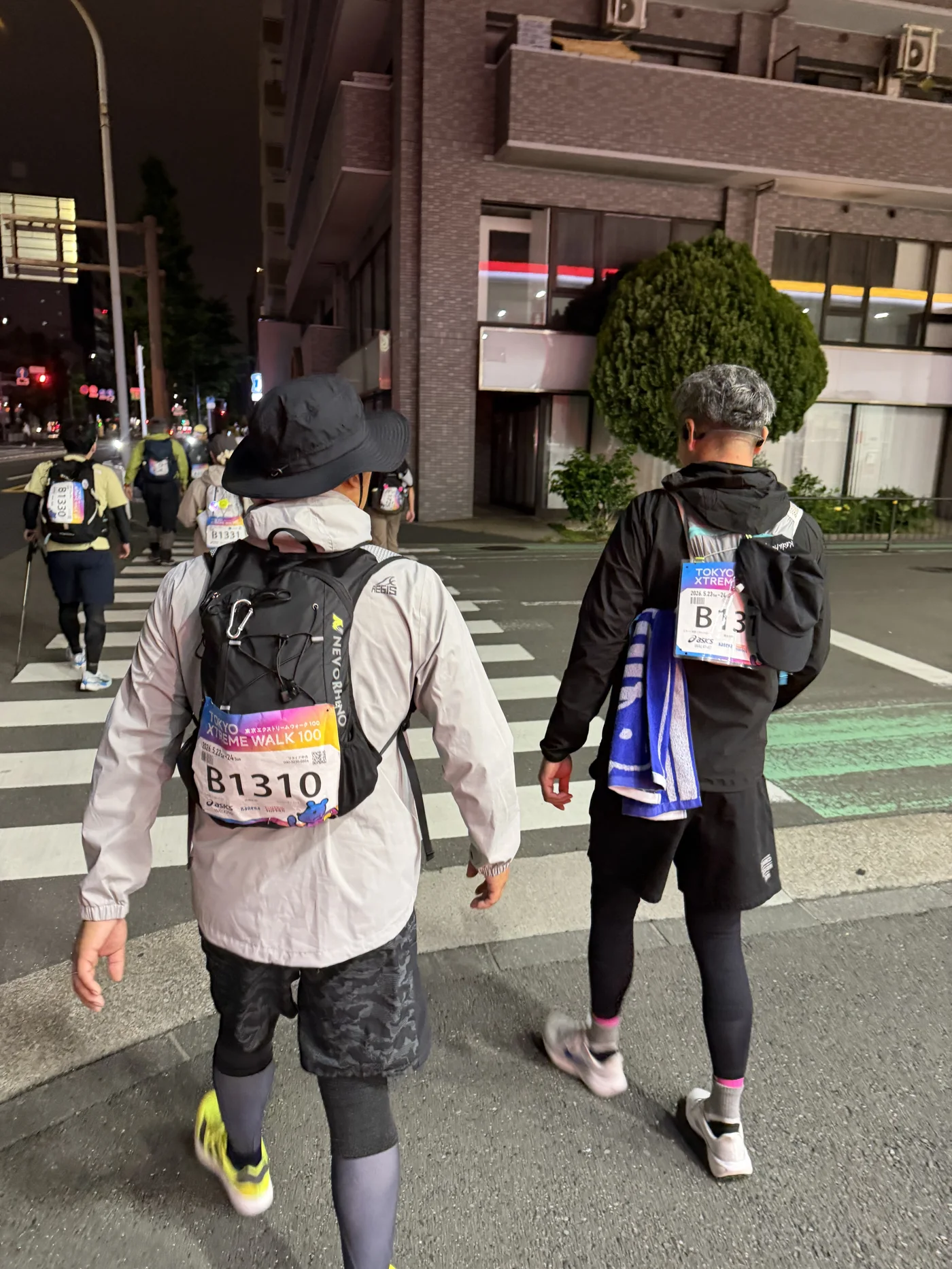 夜の橋を歩く他の参加者たち（後ろ姿）